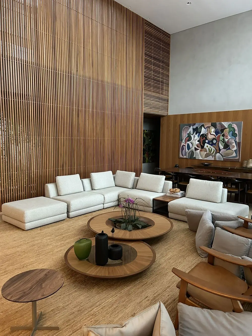 Sala com sofá modular claro e painel ripado de madeira