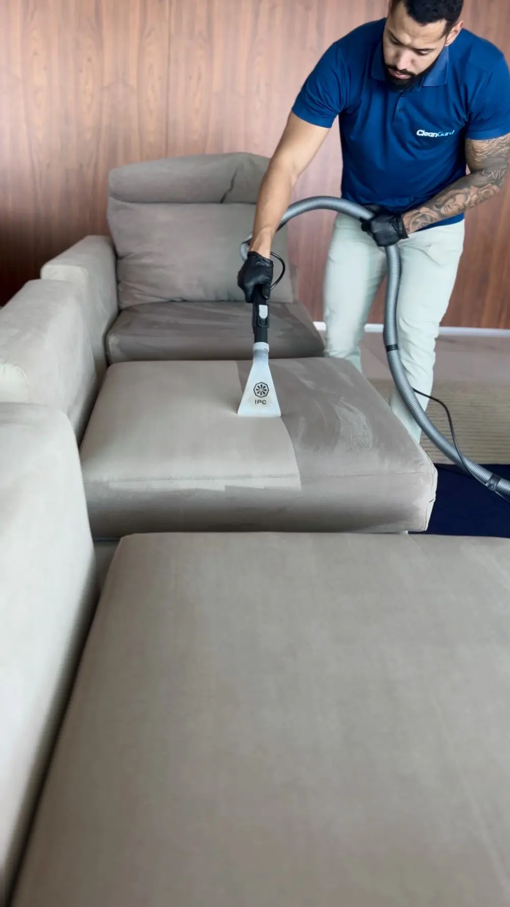 Técnico da CleanGard trabalhando em um sofá claro, com o piso protegido