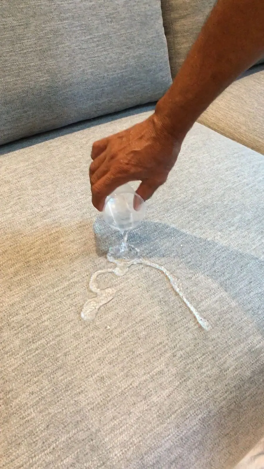 Água derramada formando gotas sobre um sofá claro impermeabilizado